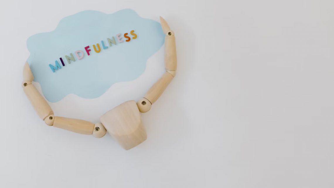 Wooden mannequin holding a mindfulness speech bubble for relaxation and mental health concepts.